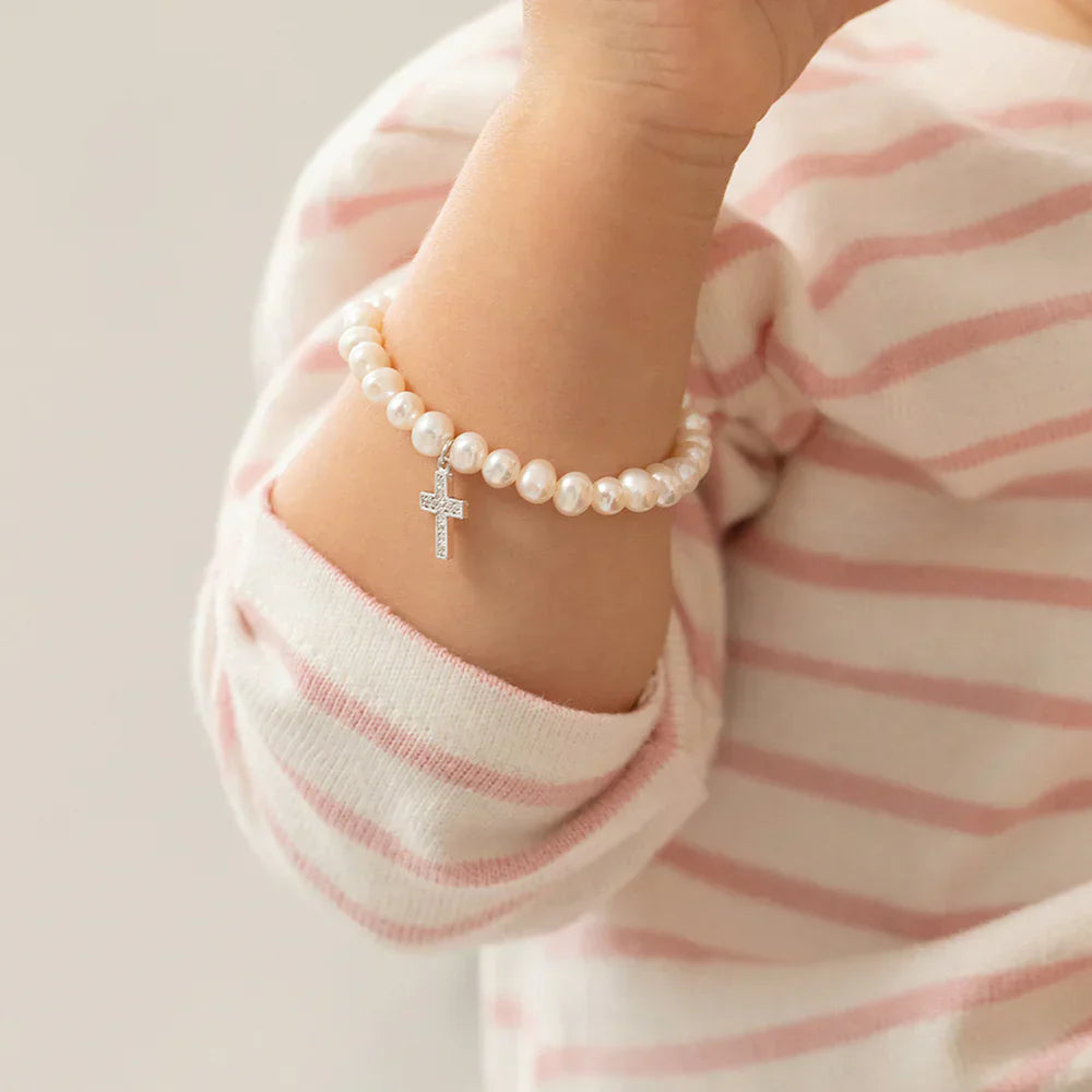 white pearl bracelet with a small silver cross charm on toddler's wrist, sterling silver toddler bracelets UK