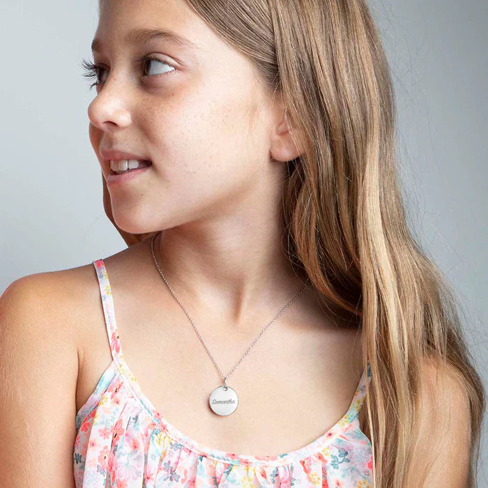 Young girl wearing a silver pendant necklace showcasing kids' necklace trends 2024 in floral dress