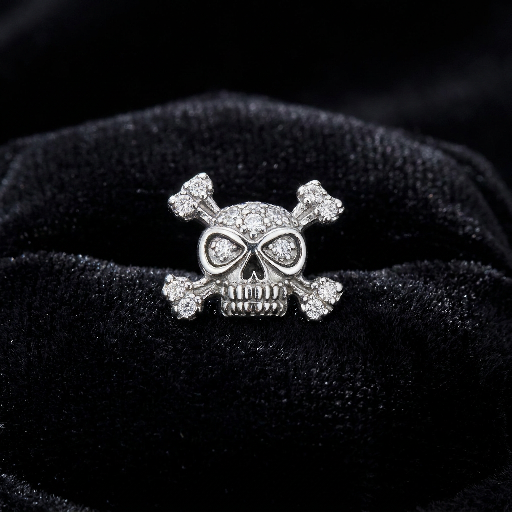 Close-up of 925 sterling silver skull and crossbones stud earring with cubic zirconia crystals on black velvet by Melchior Jewellery