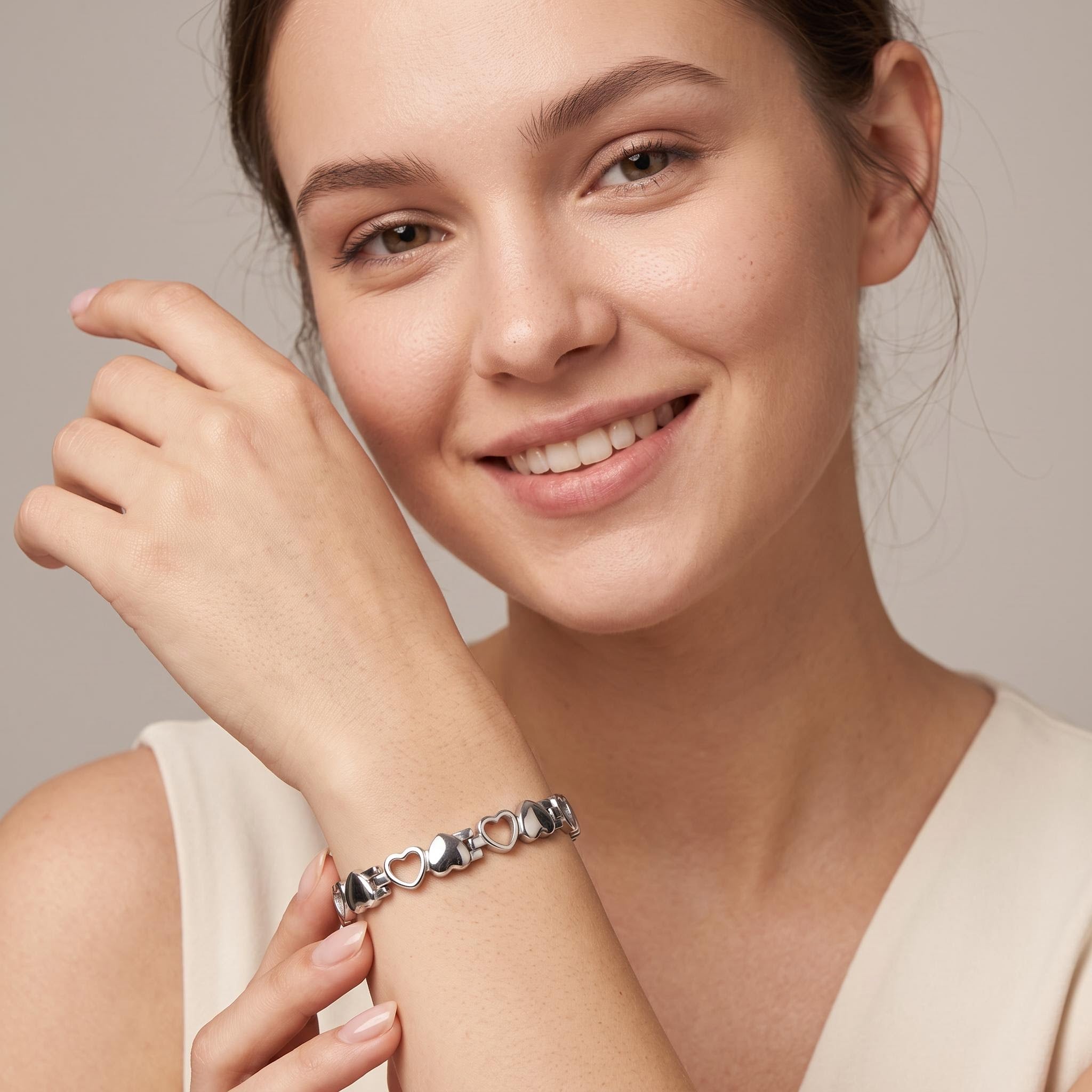A smiling woman wearing a silver magnetic therapy heart-link bracelet