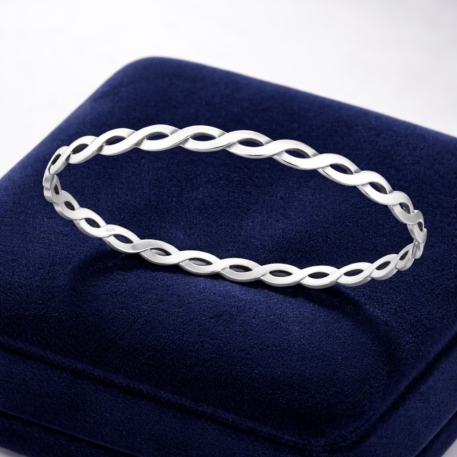 Sterling silver oxidised bangle with twisted open link design displayed on dark blue cushion