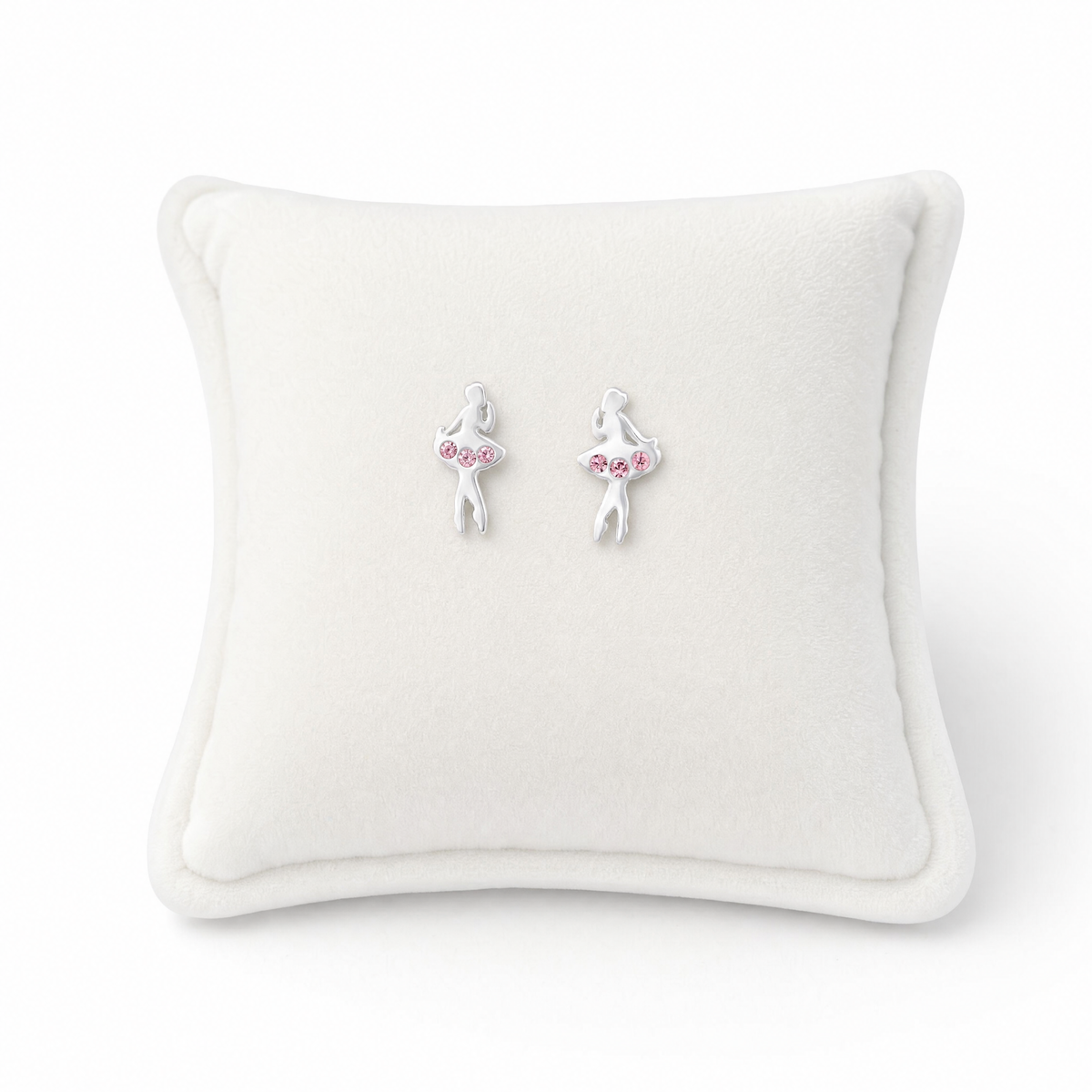 A pair of silver ballerina stud earrings with pink gem accents, displayed on a white square pillow.