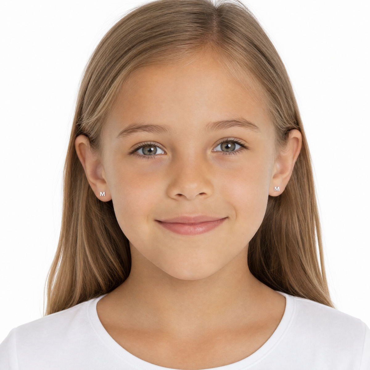 A young girl with long light brown hair wearing small silver stud earrings with a single letter 'M' on each earring
