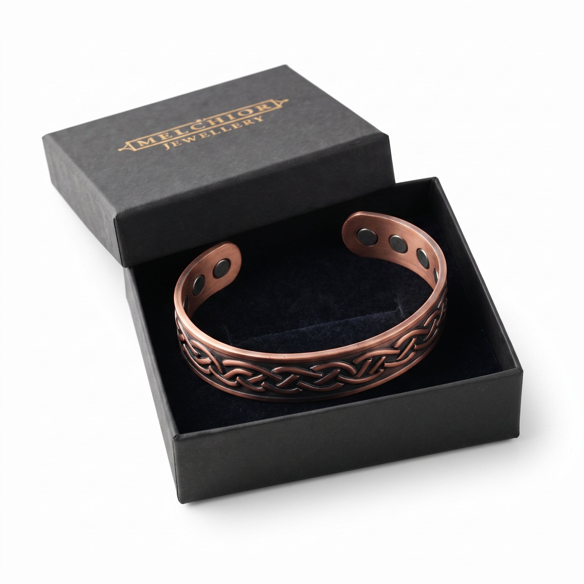 A copper-toned magnetic cuff bracelet with a Celtic knot pattern, presented in an open black gift box with a black velvet interior.