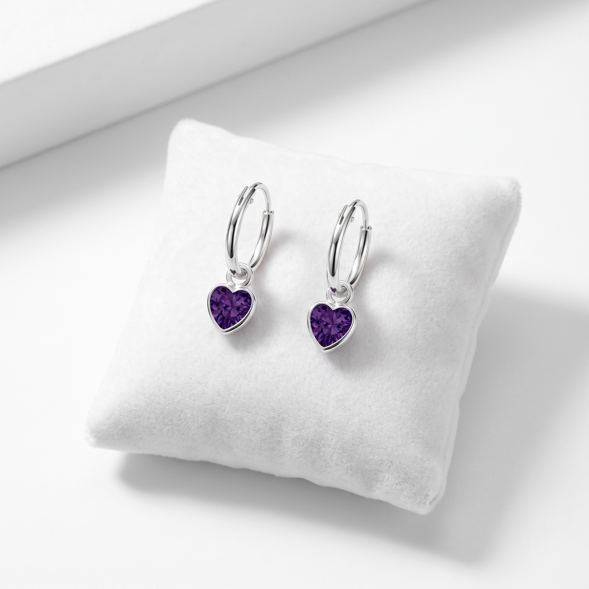 Pair of sterling silver amethyst heart CZ earrings showing the hinged fastening