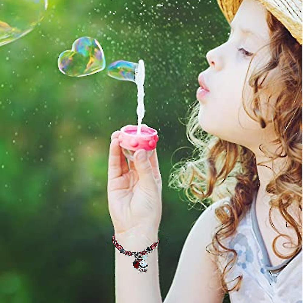 Child wearing Melchior Jewellery adjustable Santa and snowman bracelet set blowing bubbles outdoors