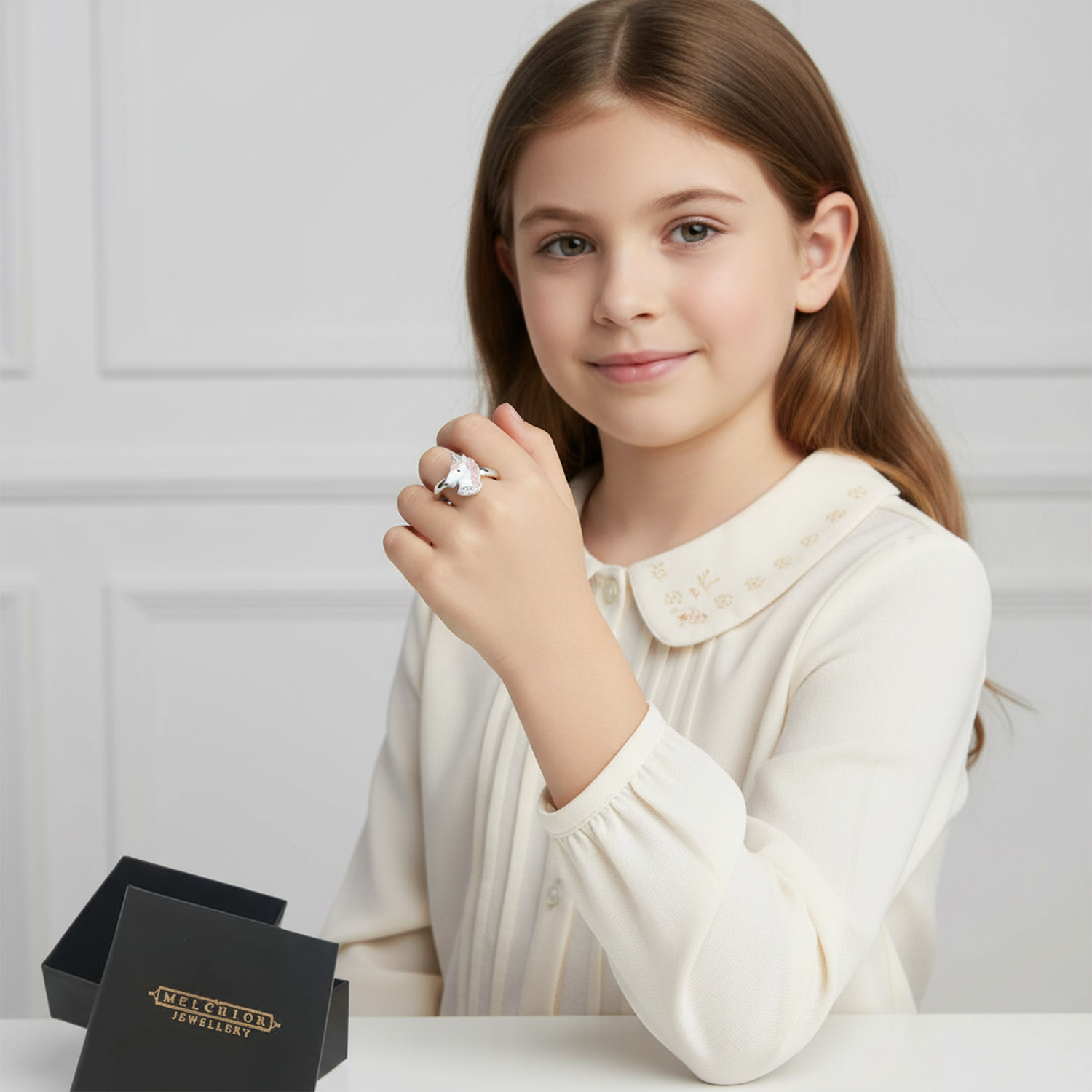 Girl wearing adjustable unicorn ring for kids by Melchior Jewellery with open black gift box on table