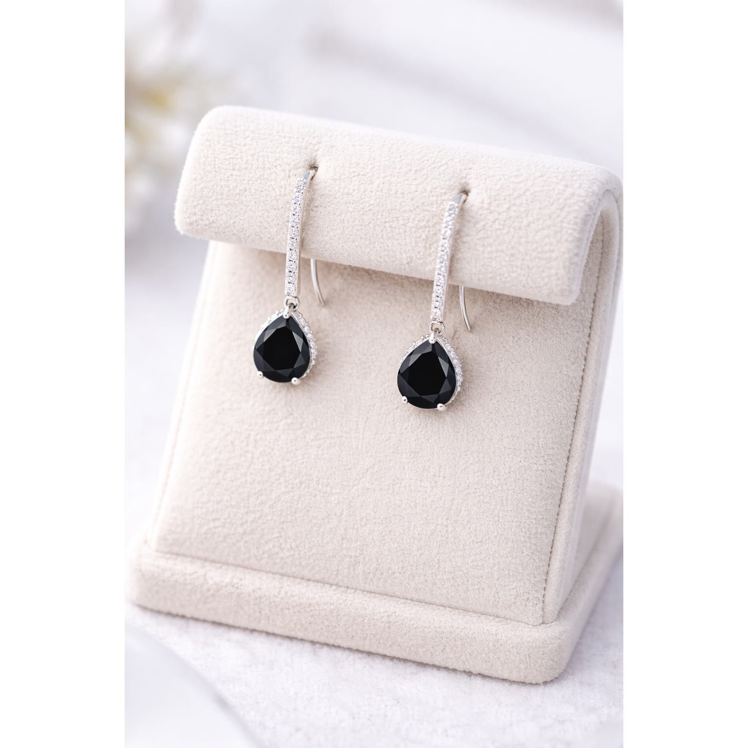 Silver Black Onyx Halo Drop Earrings by Melchior Jewellery displayed on a beige stand