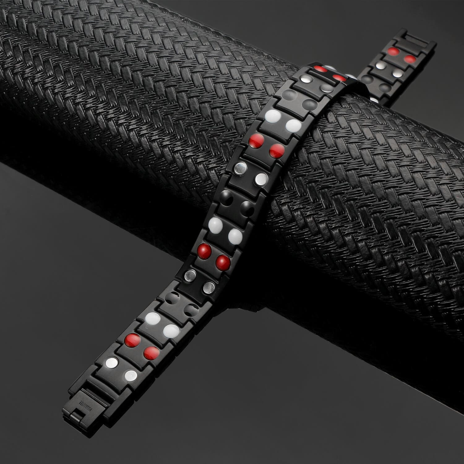 Black titanium magnetic bracelet by Melchior Jewellery featuring red and silver magnetic elements on a textured black background
