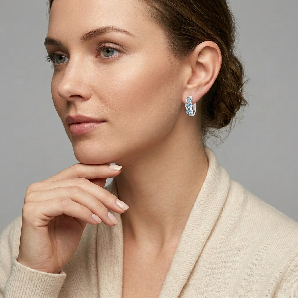 Melchior Jewellery silver huggie hoop earrings with light blue gemstones worn by model in cream top