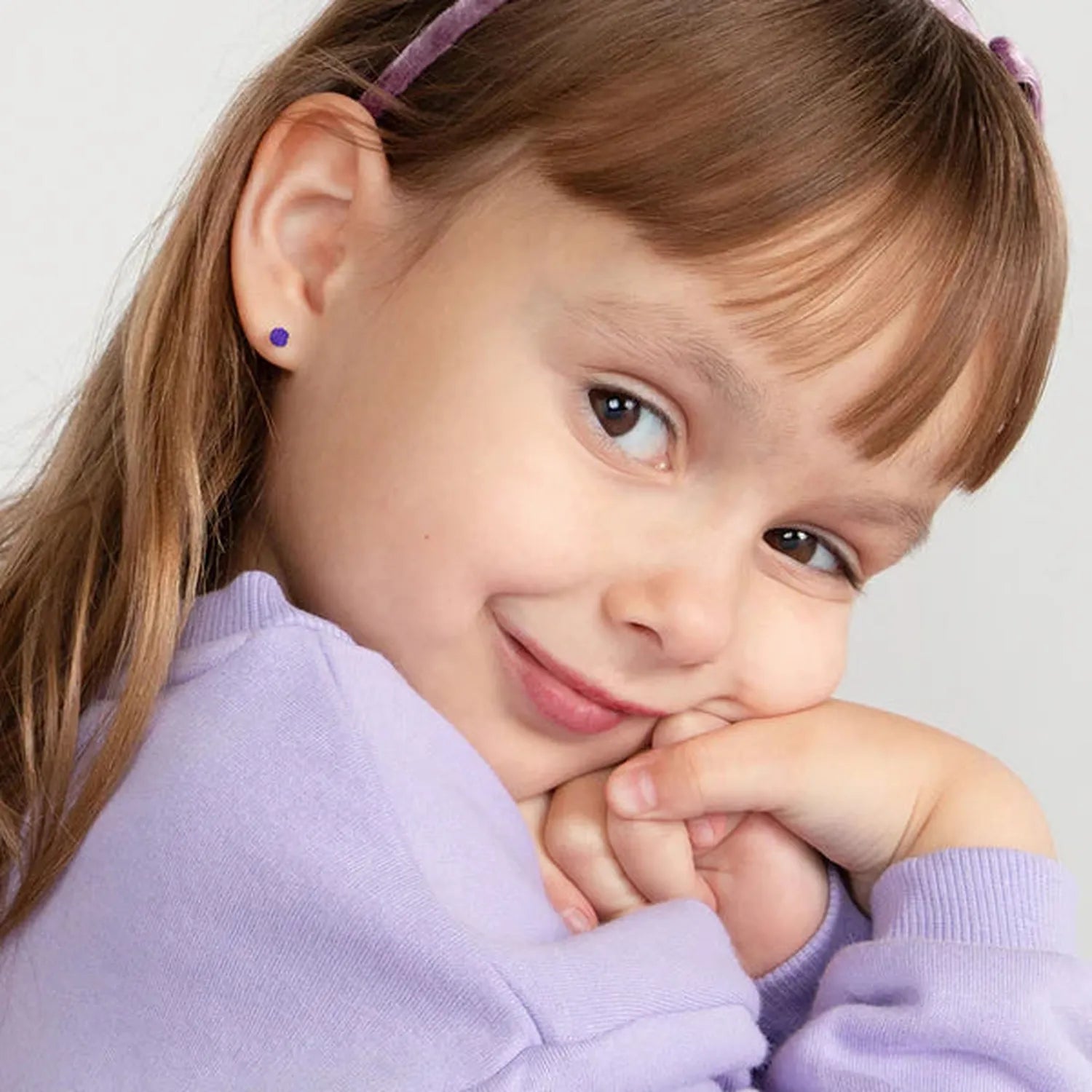 Child wearing 14k gold February birthstone earrings with purple gemstone stud from In Season Jewellery