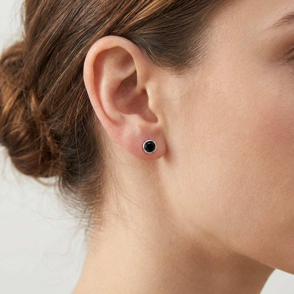 Woman wearing sterling silver 5mm round black cubic zirconia stud earring, close-up lifestyle shot