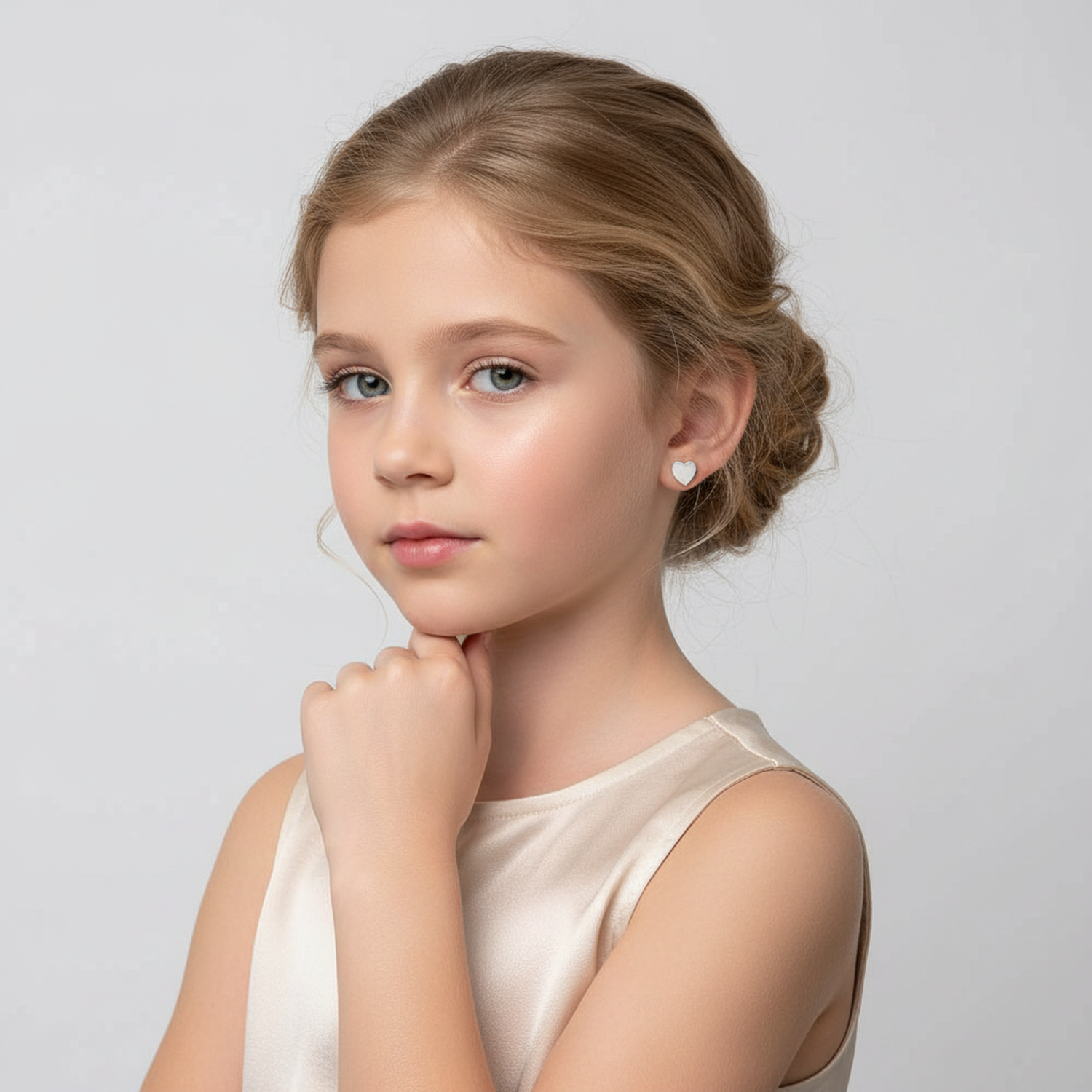 Young girl wearing girls sterling silver heart stud earrings from Melchior Jewellery with a thoughtful pose
