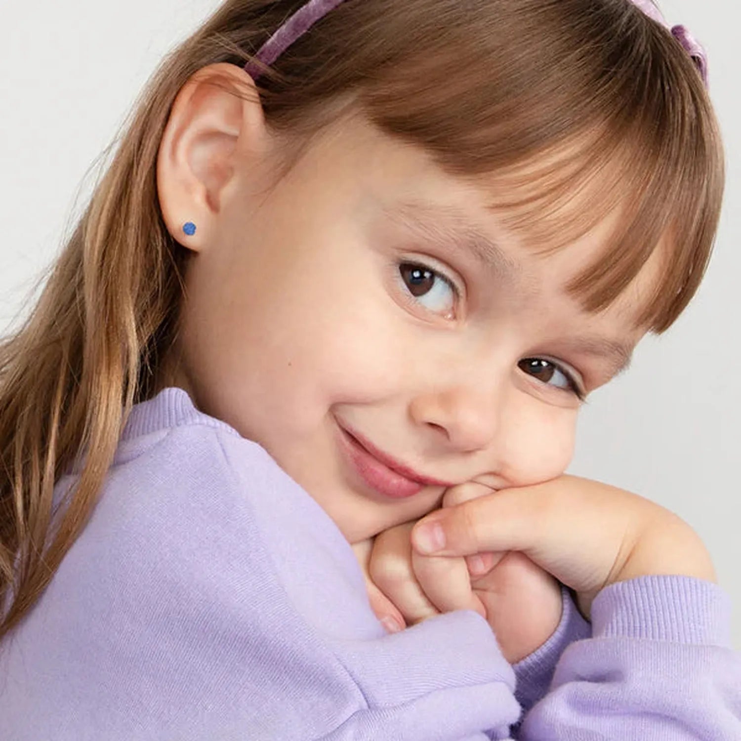 14k gold December birthstone earrings with blue stones on child wearing lilac jumper