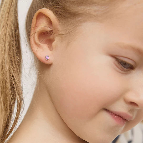 In Season Jewellery pink gemstone studs on a smiling child showcasing girls screw back earrings for safety