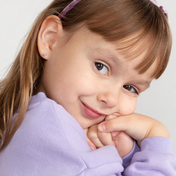 Young girl wearing 14k gold October birthstone earrings for kids with a purple top and headband