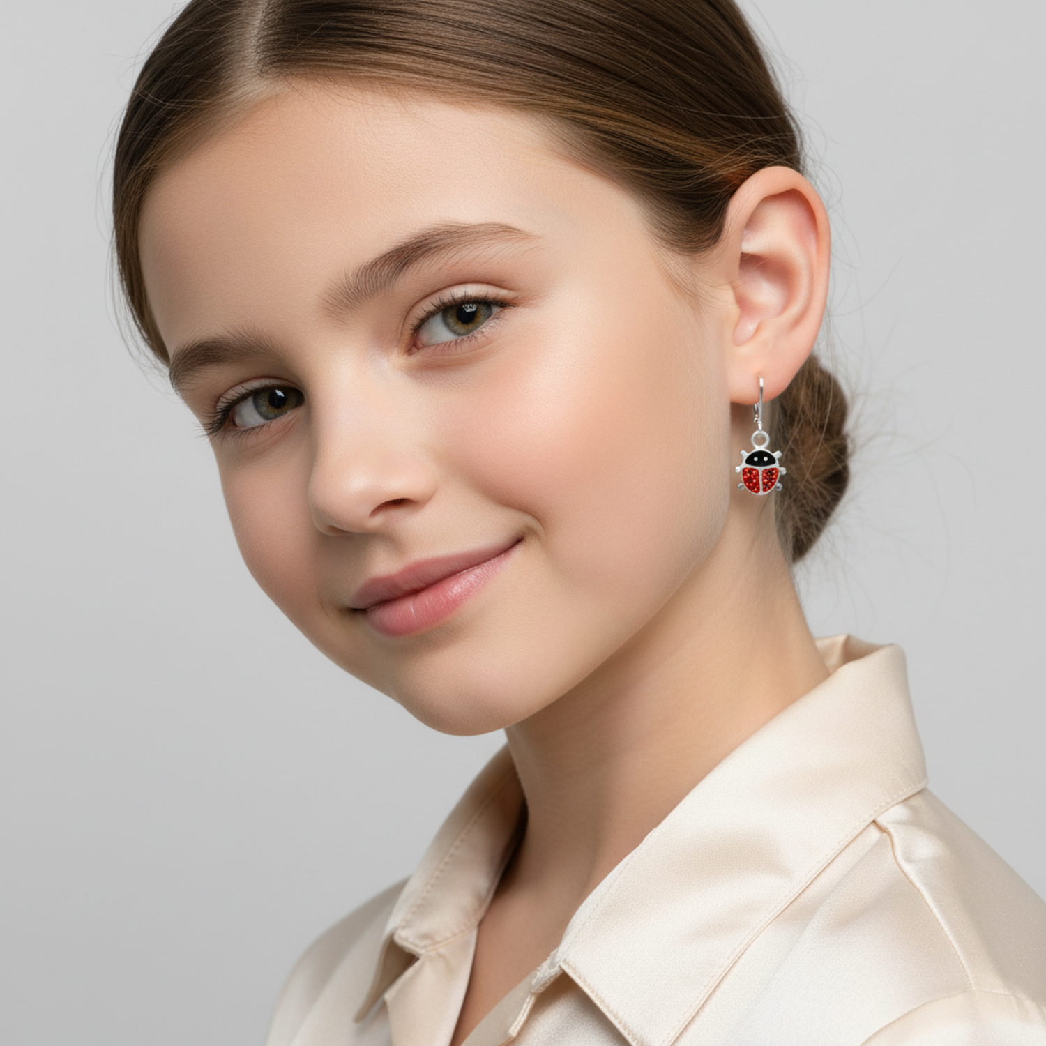 Melchior Jewellery kids sparkly ladybird leverback earrings worn by a smiling young girl with brown hair