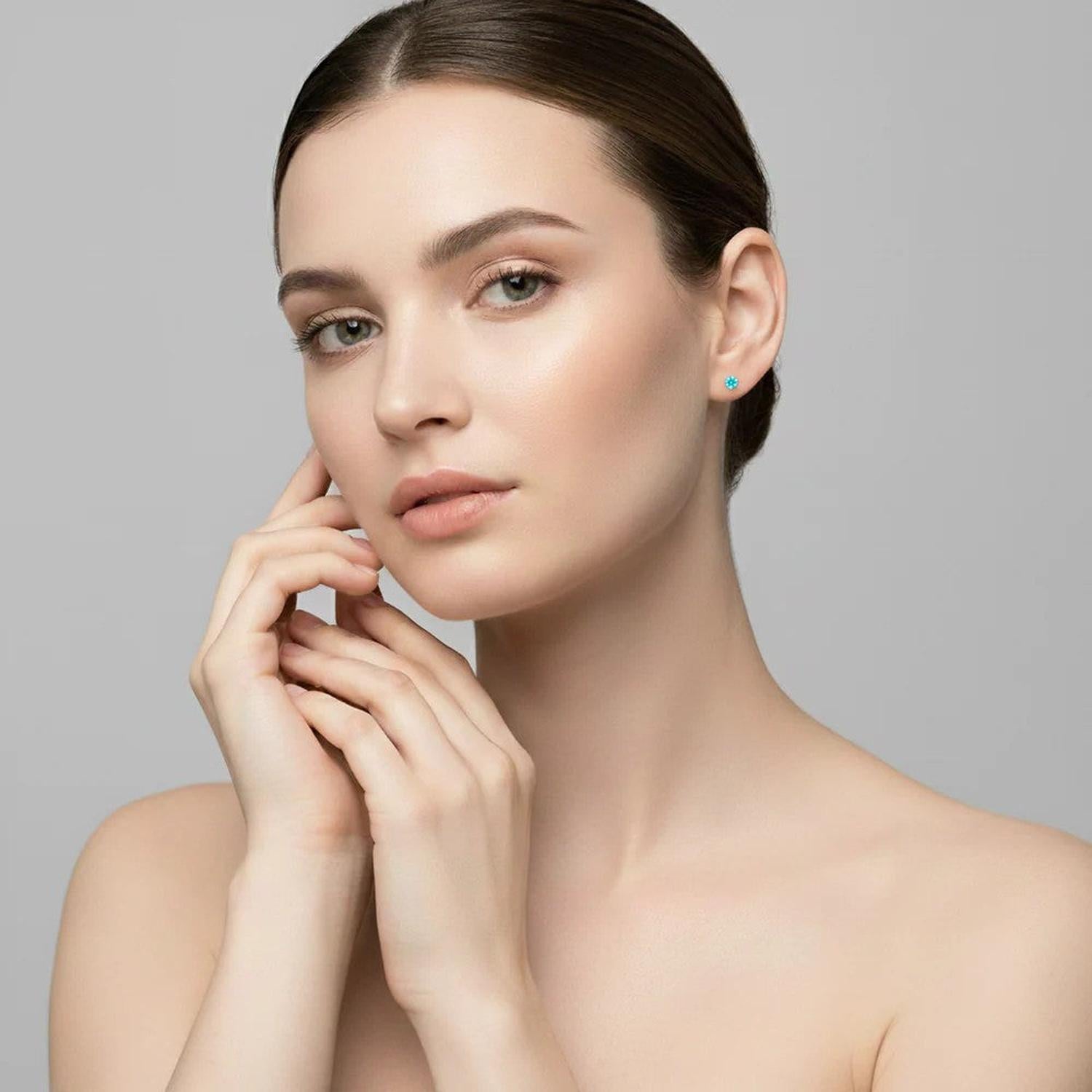 Elegant 4mm round cubic zirconia earrings with vibrant turquoise colour worn by model with neutral makeup