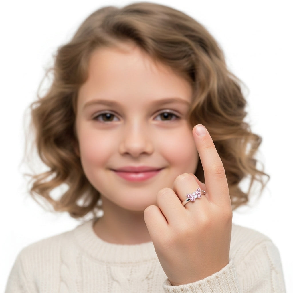 Adjustable pink butterfly ring for girls worn by young girl with curly hair and cream sweater