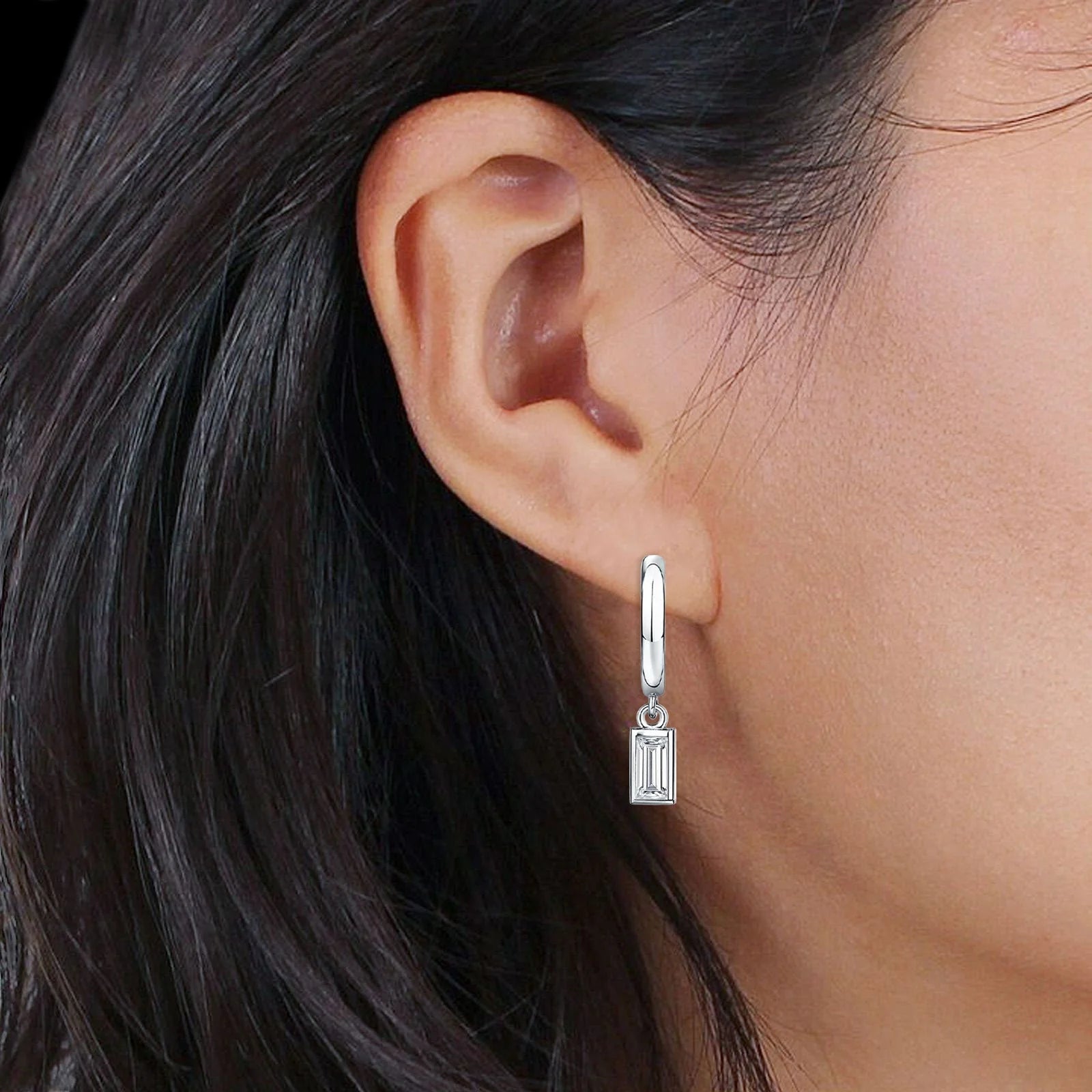 Silver baguette cz hoop earrings by Melchior Jewellery worn on ear with black hair background