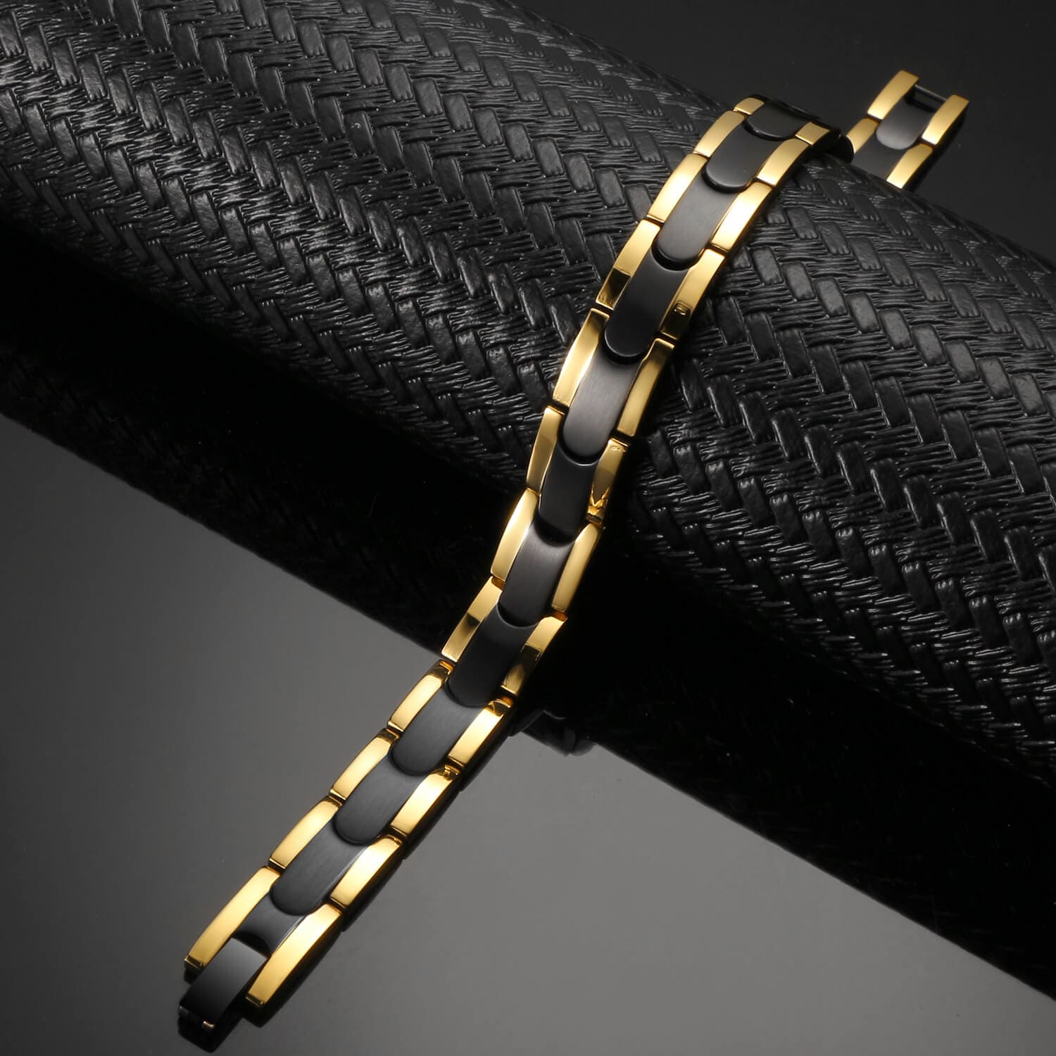 Melchior Jewellery black gold titanium magnetic bracelet with polished linked design on textured black backdrop