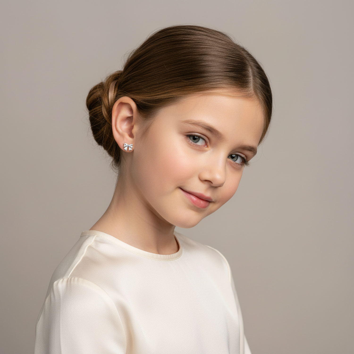 Young girl wearing bow design silver earrings from Melchior Jewellery in a cream blouse