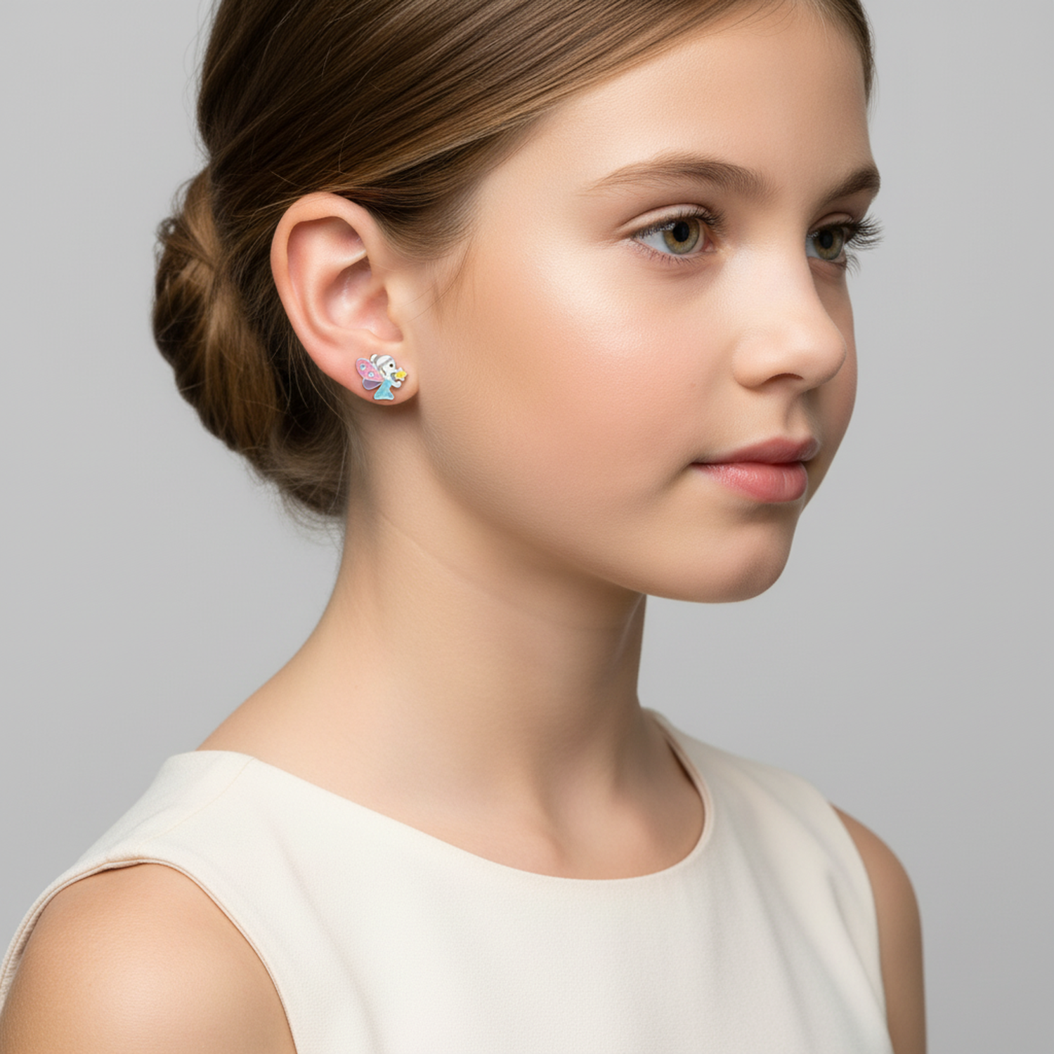 Child wearing childrens silver fairy stud earrings with blue wings and yellow details from Melchior Jewellery
