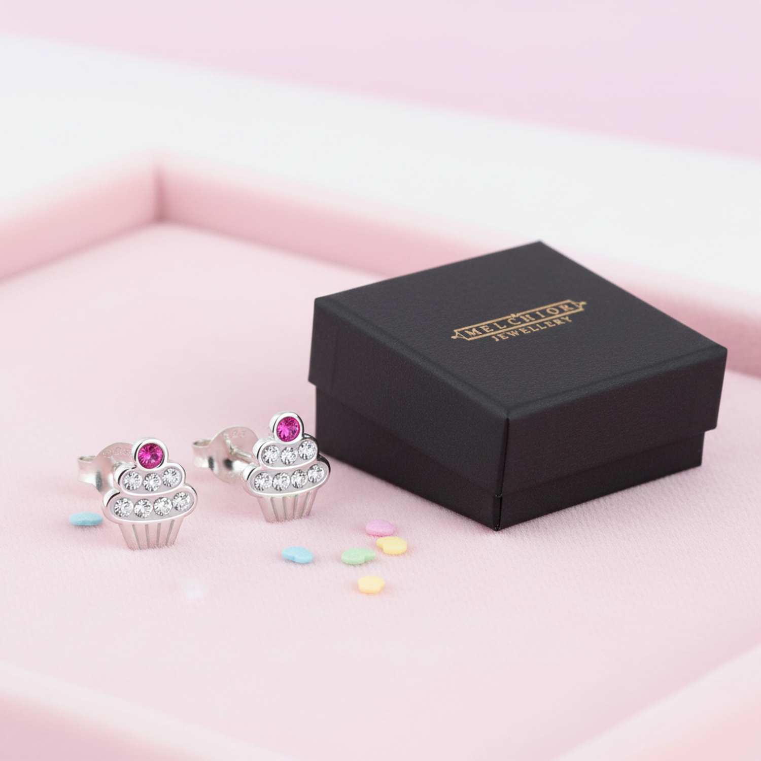 Melchior Jewellery cupcake ear studs for kids silver earrings with pink and clear stones displayed beside black jewellery box