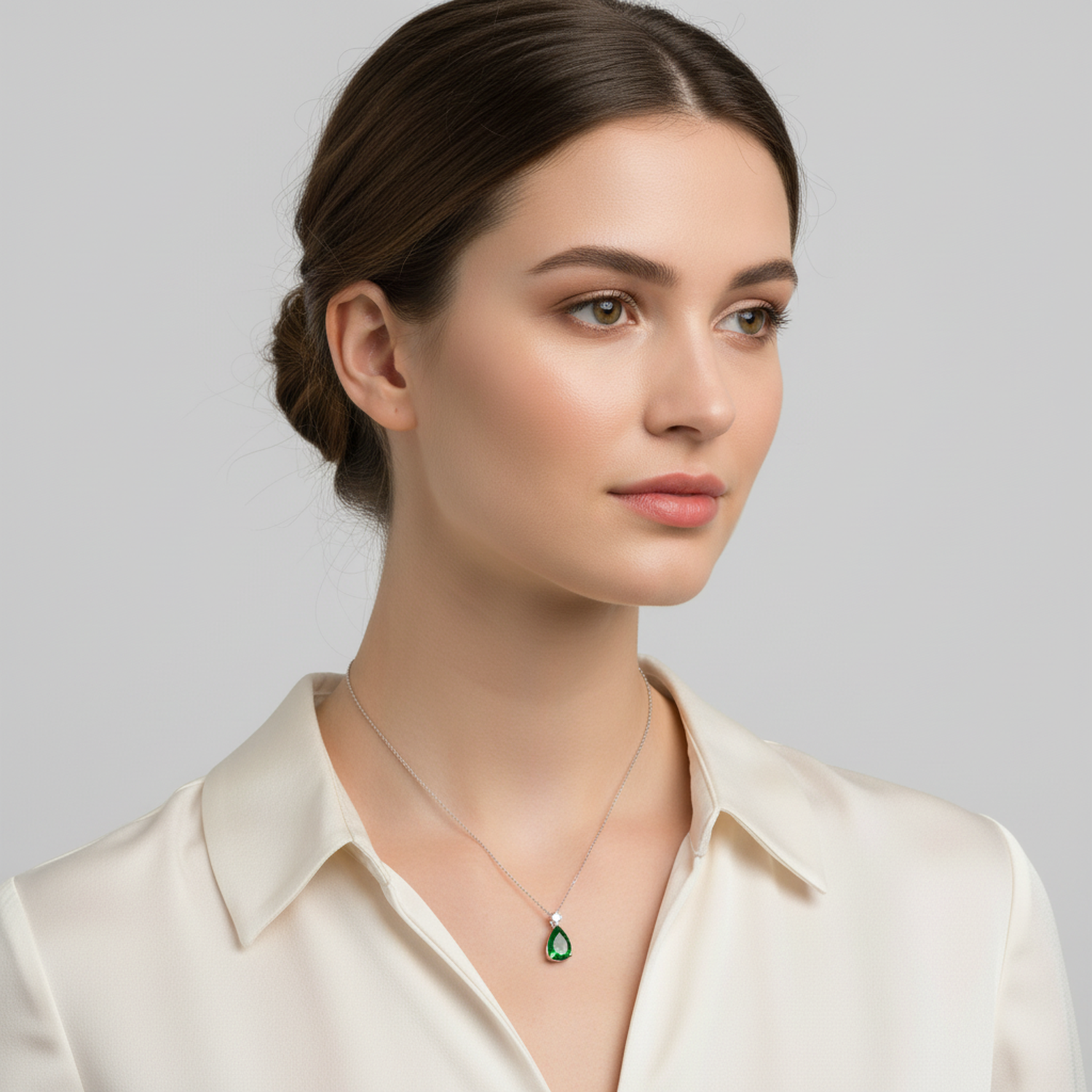 Sentiell woman wearing a cz emerald teardrop pendant necklace with a silver chain and cream blouse