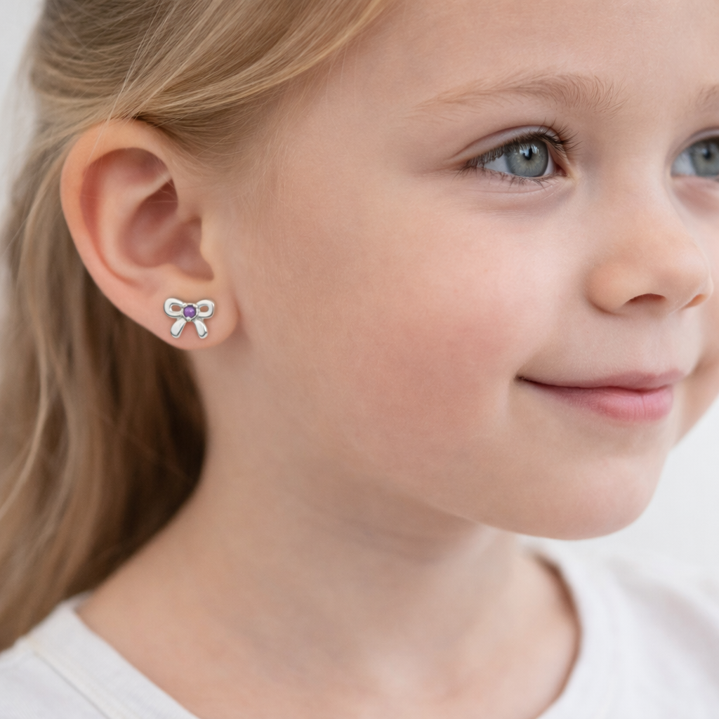 Girls amethyst birthstone earrings from Melchior Jewellery worn by young girl with silver bow design