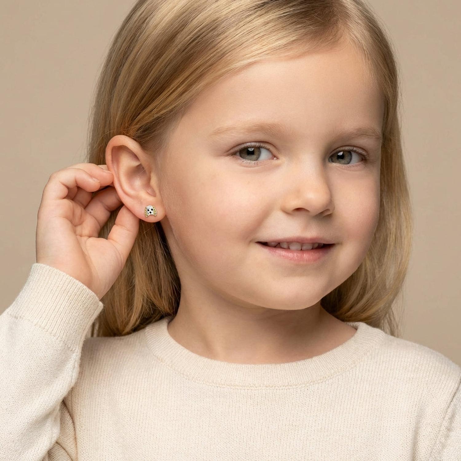 Young girl wearing Melchior Jewellery girls dog stud earrings in white with black and gold details