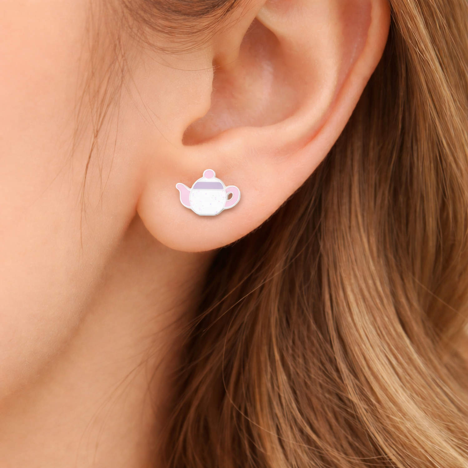 Girls novelty silver earrings shaped like a teapot worn on a child's ear by Melchior Jewellery