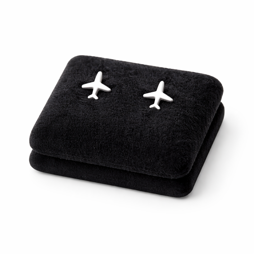 Melchior Jewellery hypoallergenic kids earrings shaped like small silver aeroplanes on black cushion