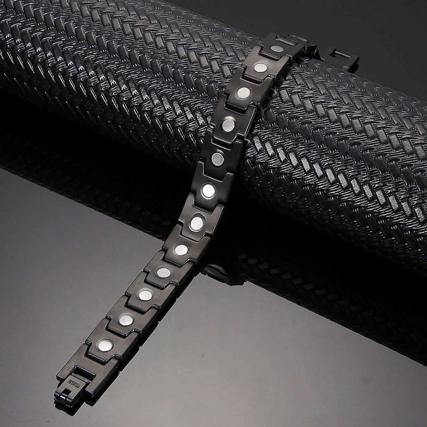 Melchior Jewellery black titanium magnetic bracelet for women displayed on textured black surface with link design and magnets