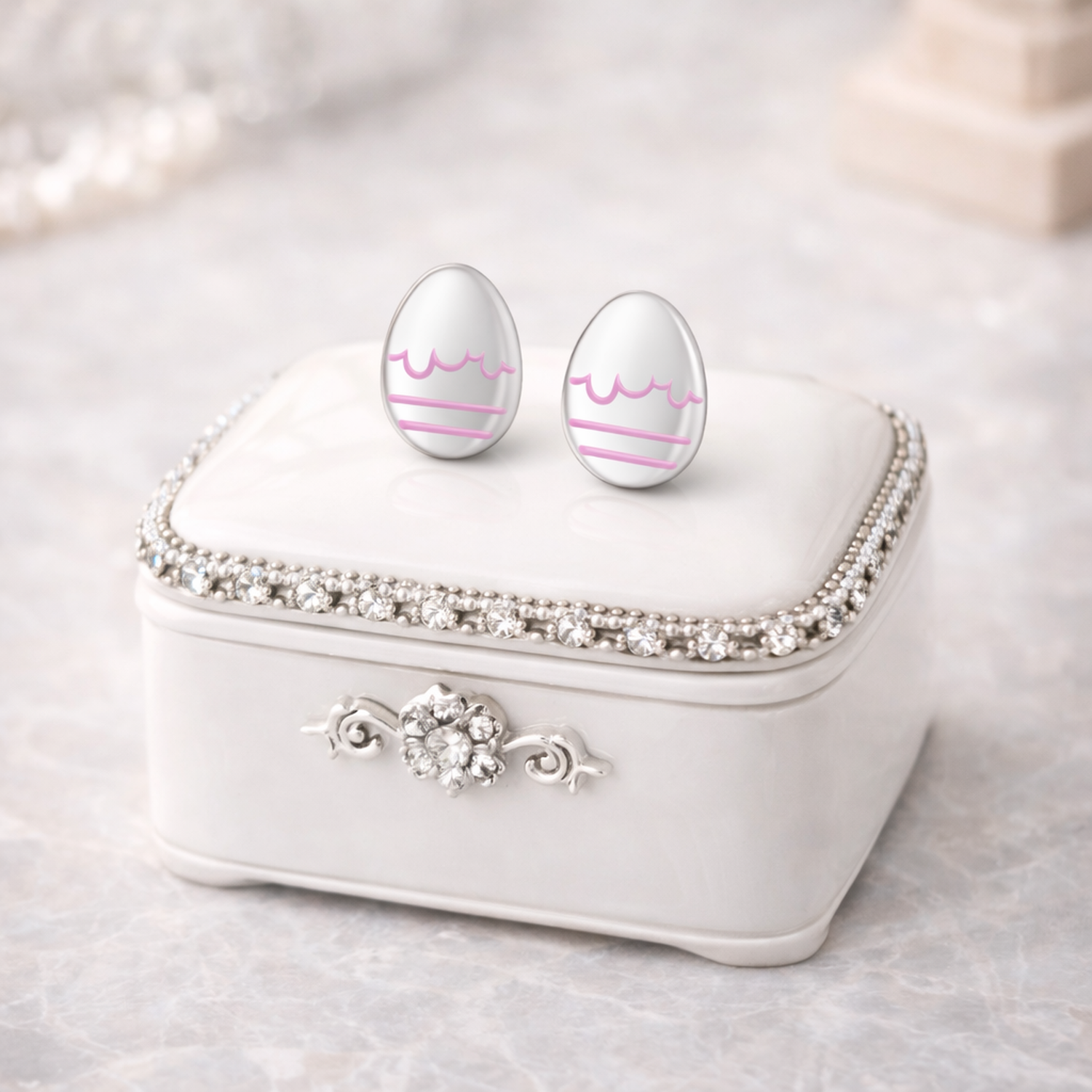 Melchior Jewellery kids hypoallergenic stud easter earrings shaped like white eggs with pink decoration on a jeweled white box