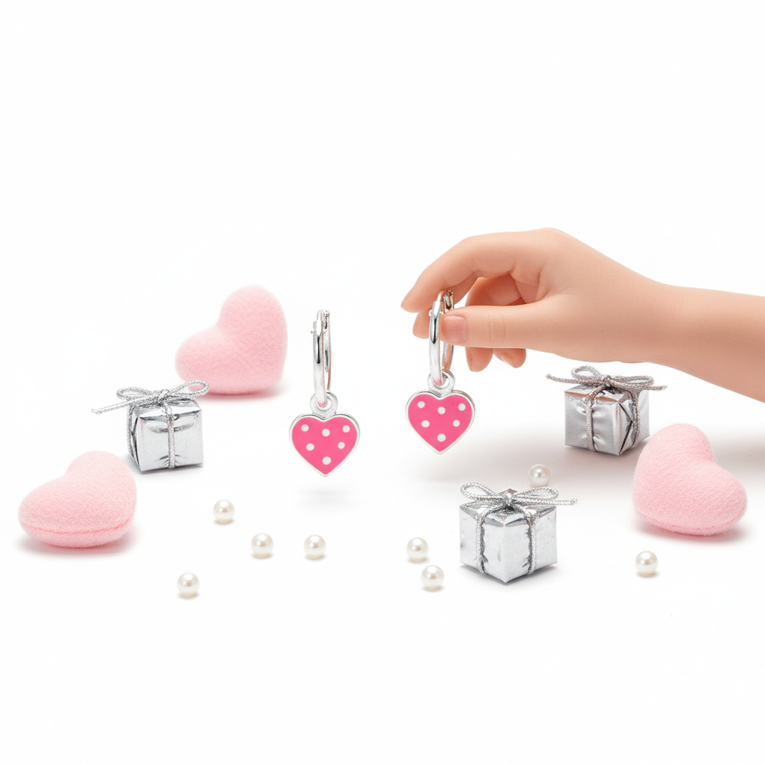 Kids spotted heart hoop earrings in pink with silver hoops held by child’s hand and gift boxes
