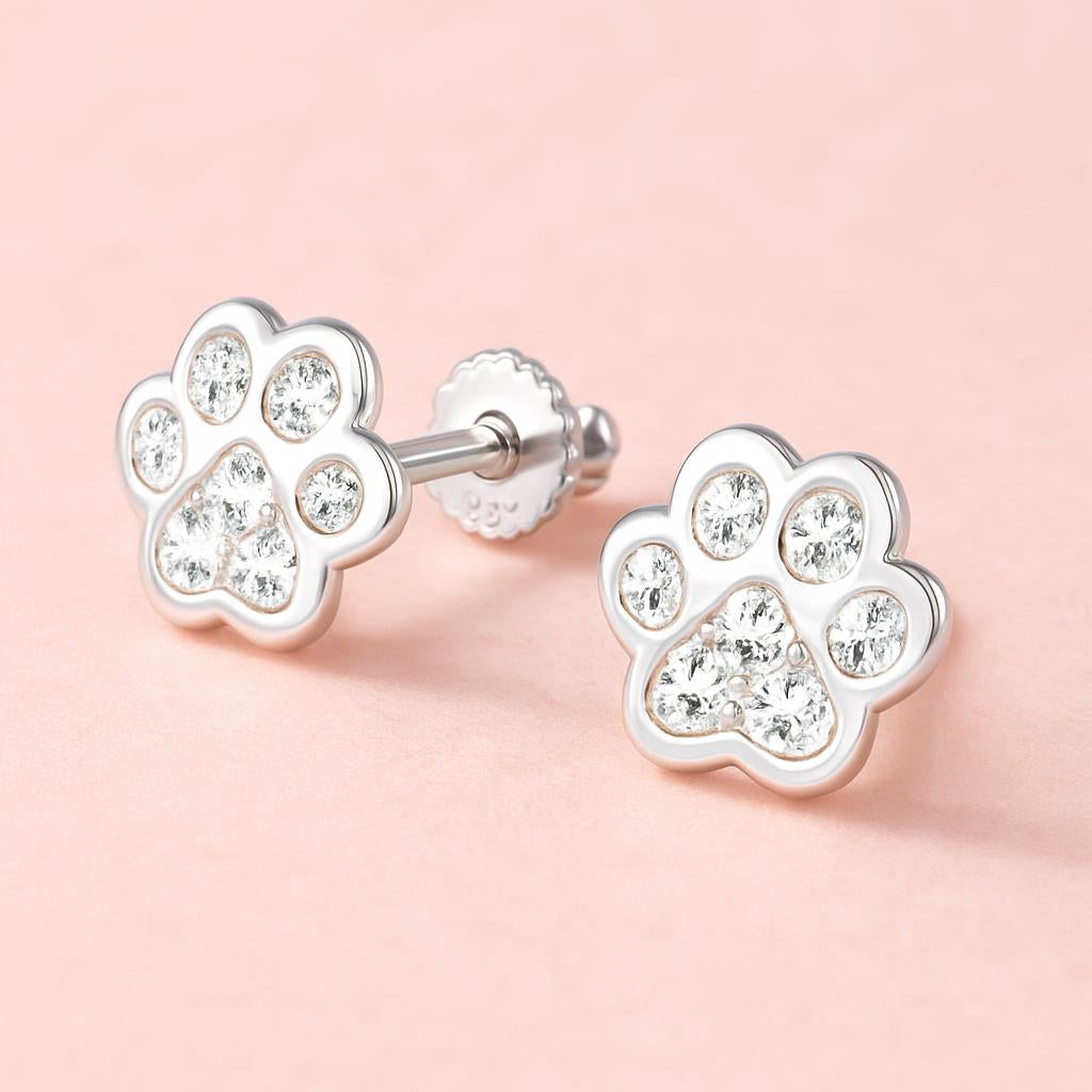 Melchior Jewellery kids sterling silver paw earrings studded with clear crystals on a pink background