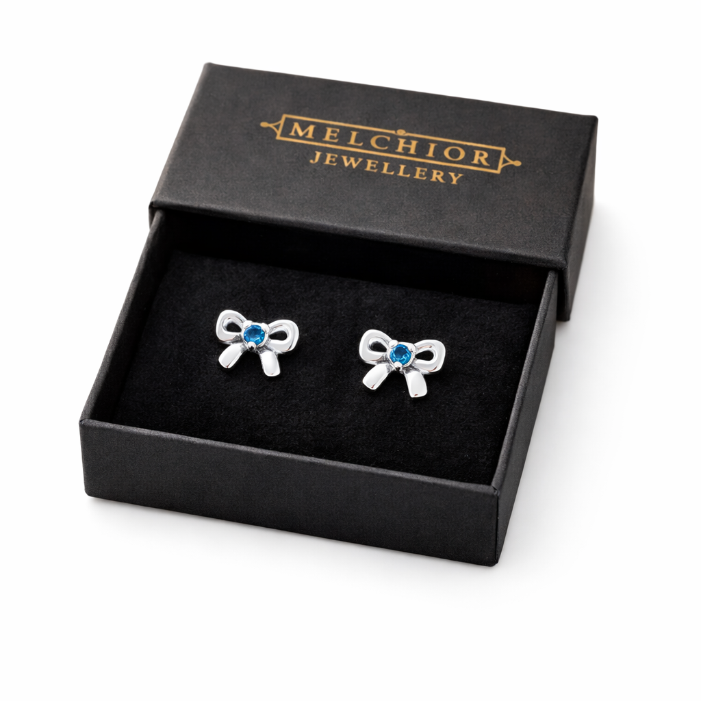 Melchior Jewellery March birthstone earrings for kids shaped like silver bows with blue stones in black box