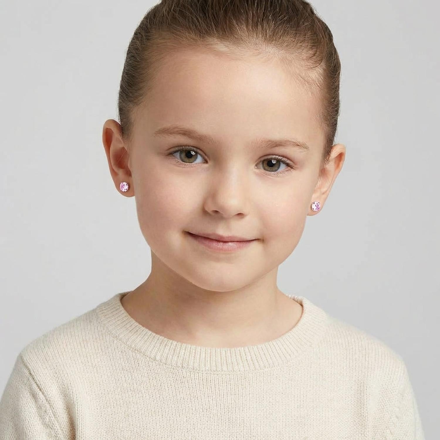 Young girl wearing pink crystal earrings for girls by Melchior Jewellery with a simple cream sweater