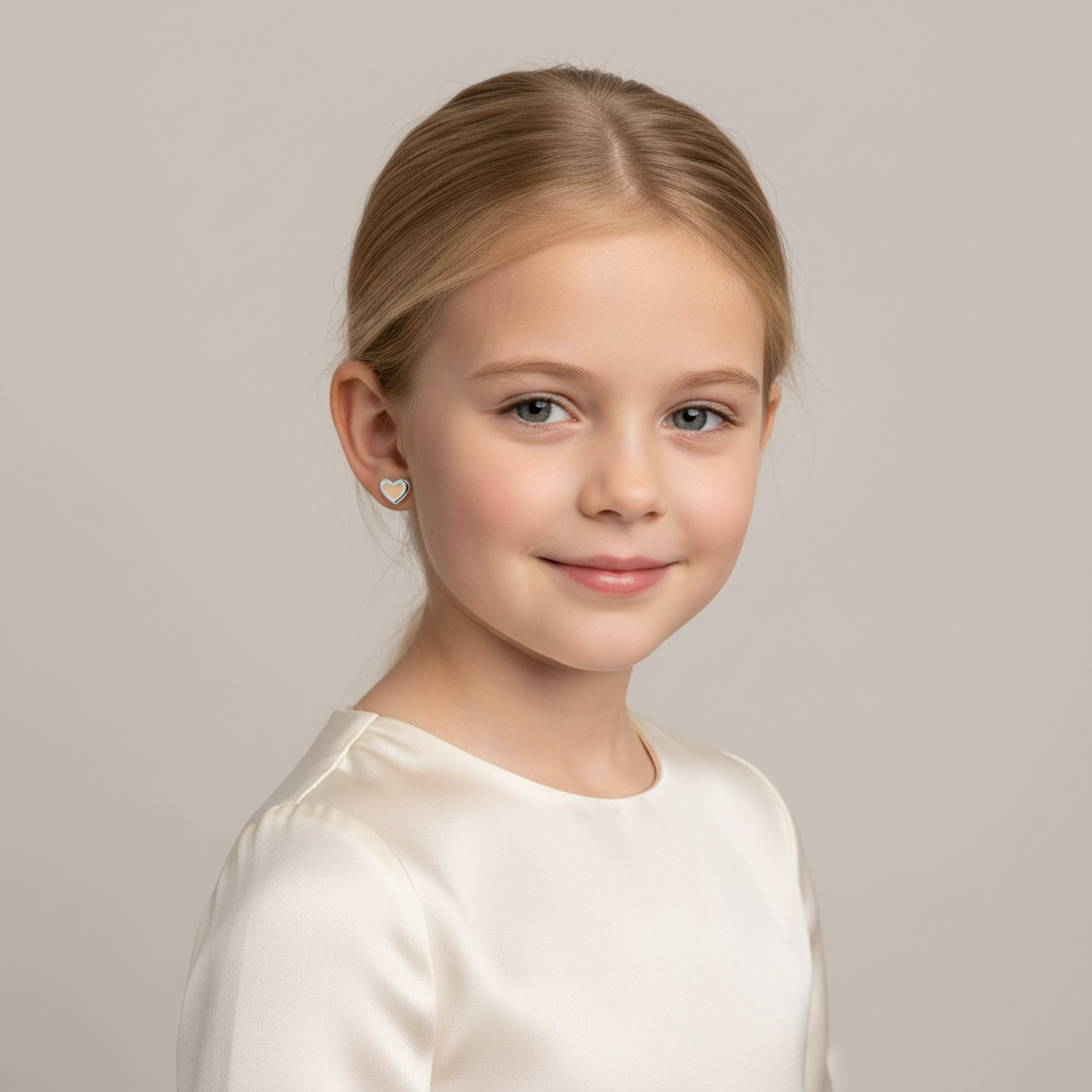 Young girl wearing pink heart stud earrings for girls by Melchior Jewellery with a soft smile