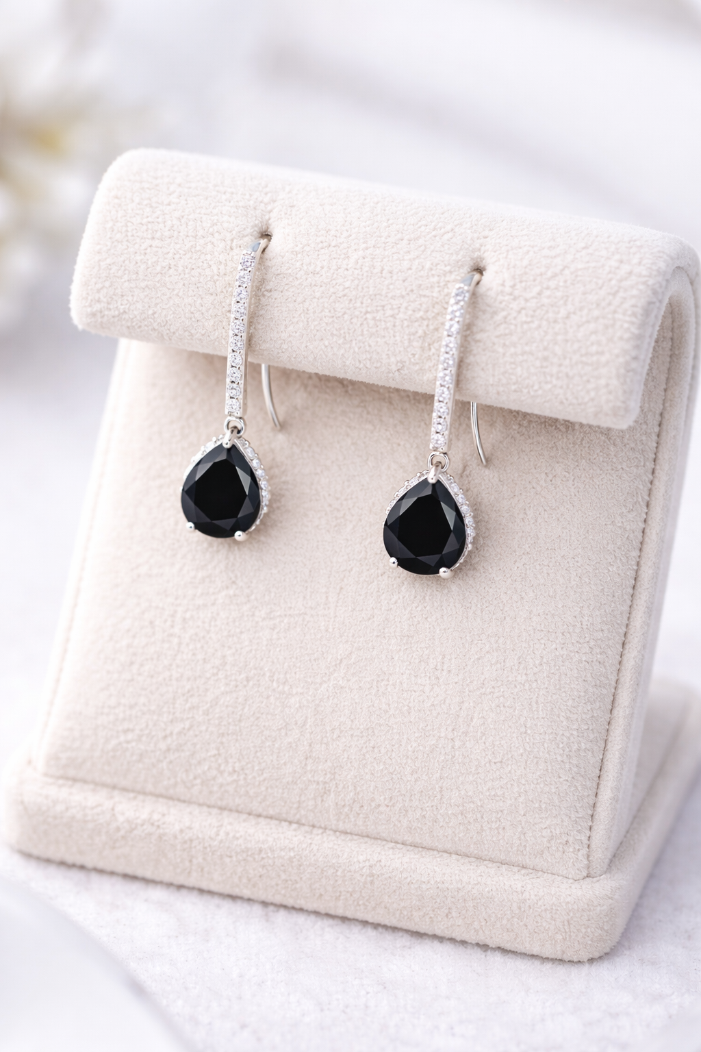 Silver Black Onyx Halo Drop Earrings by Melchior Jewellery displayed on a beige stand