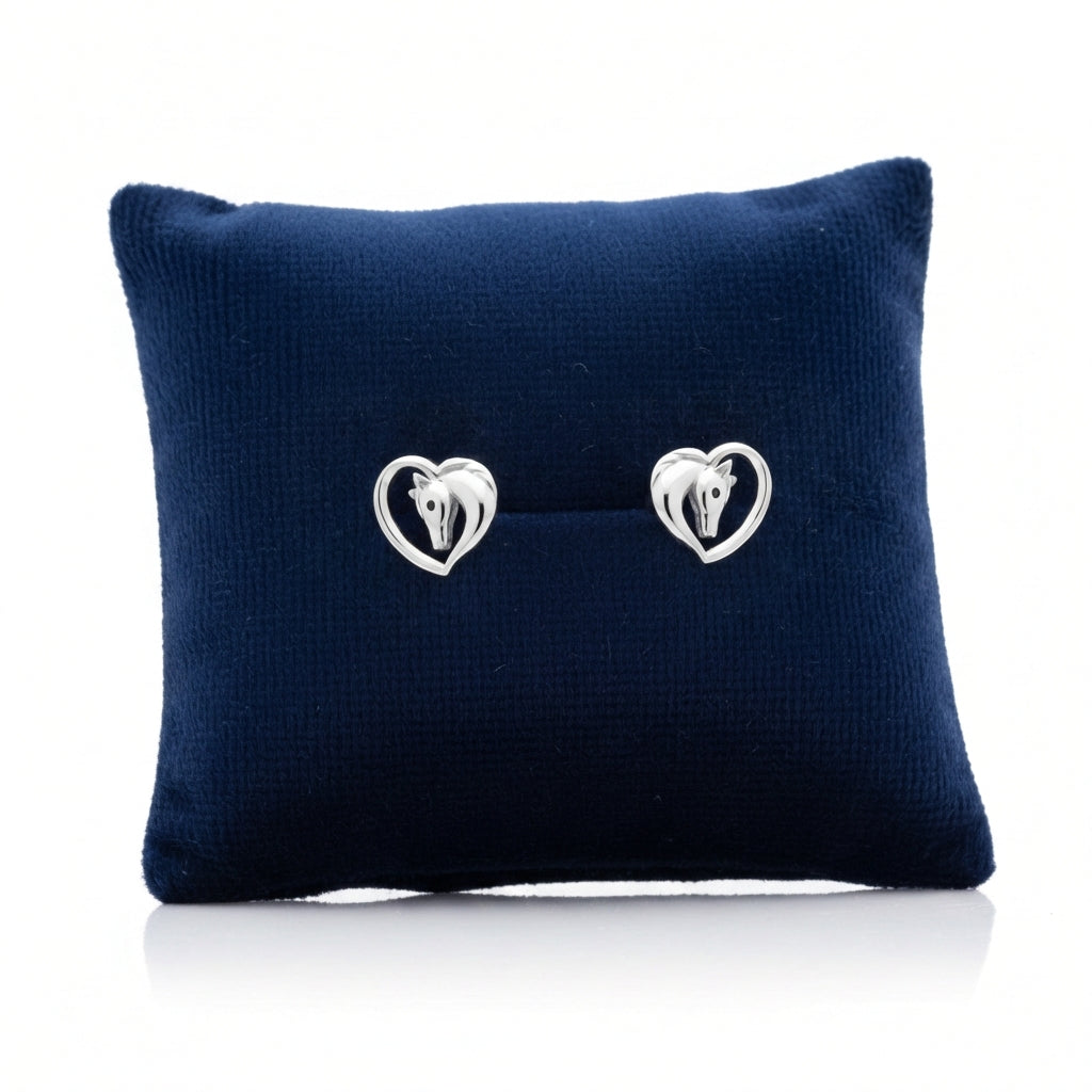 Silver heart horse earrings by Melchior Jewellery displayed on a navy blue cushion for women
