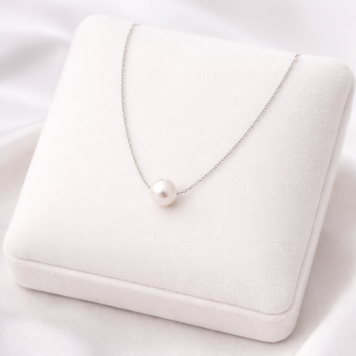 sterling silver freshwater pearl necklace with delicate chain displayed on white jewellery cushion