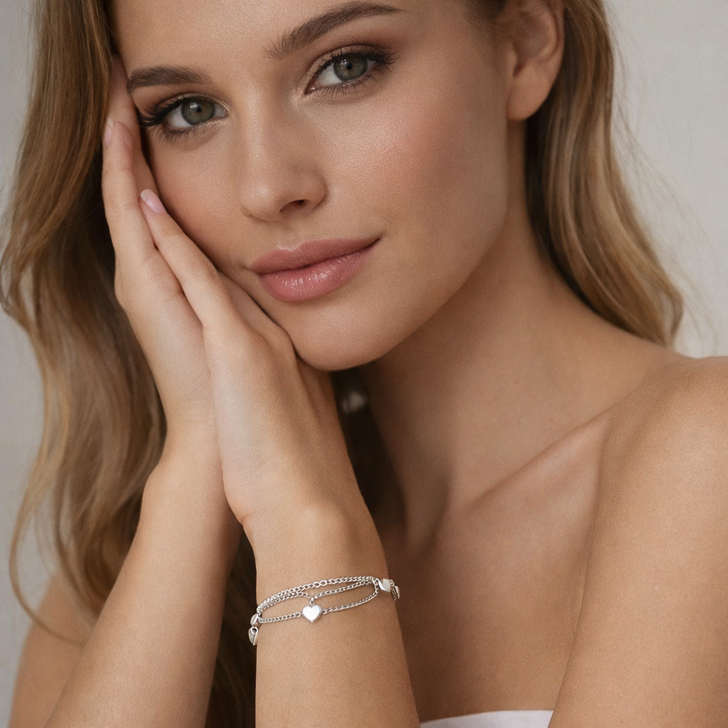 Melchior Jewellery woman's wrist wearing a delicate sterling silver heart charm bracelet with layered chains