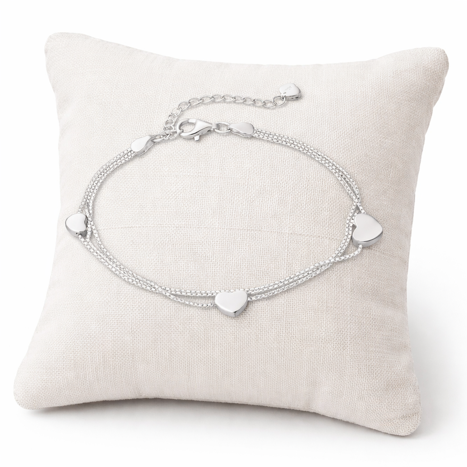 Sterling silver heart charm bracelet by Melchior Jewellery displayed on a beige cushion