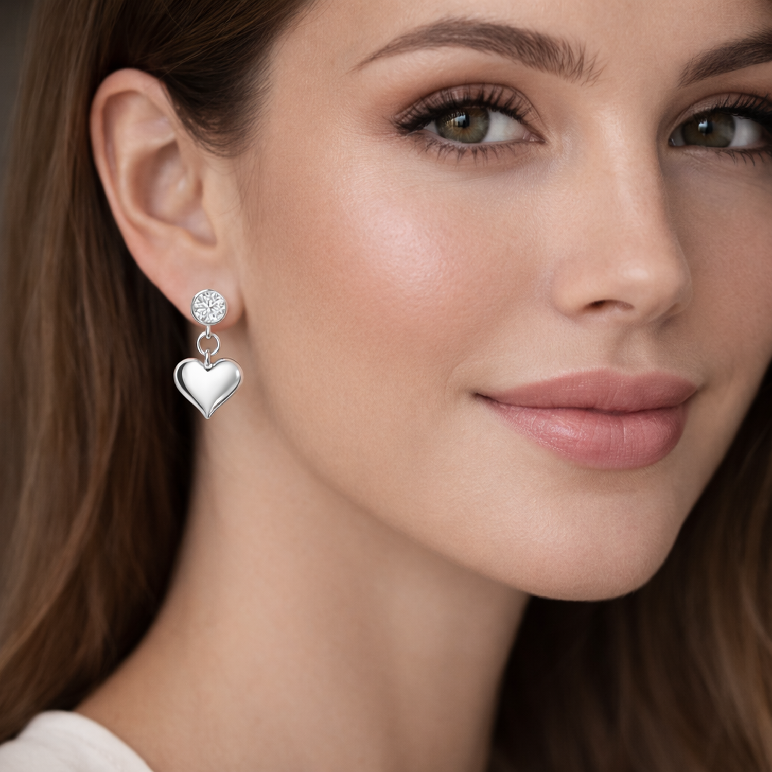 Close up of a woman wearing Melchior Jewellery sterling silver heart drop earrings with a polished finish