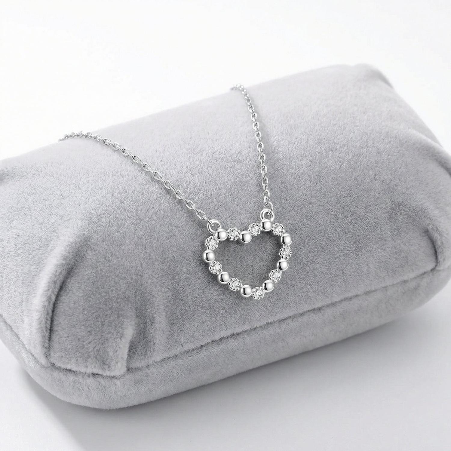 Sentiell sterling silver heart necklace for woman displayed on grey velvet cushion