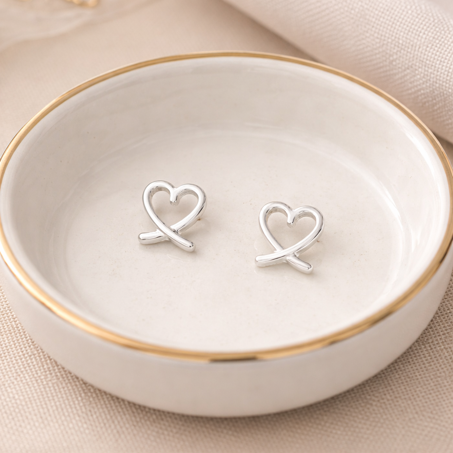 Melchior Jewellery sterling silver heart stud earrings on a ceramic plate with gold rim
