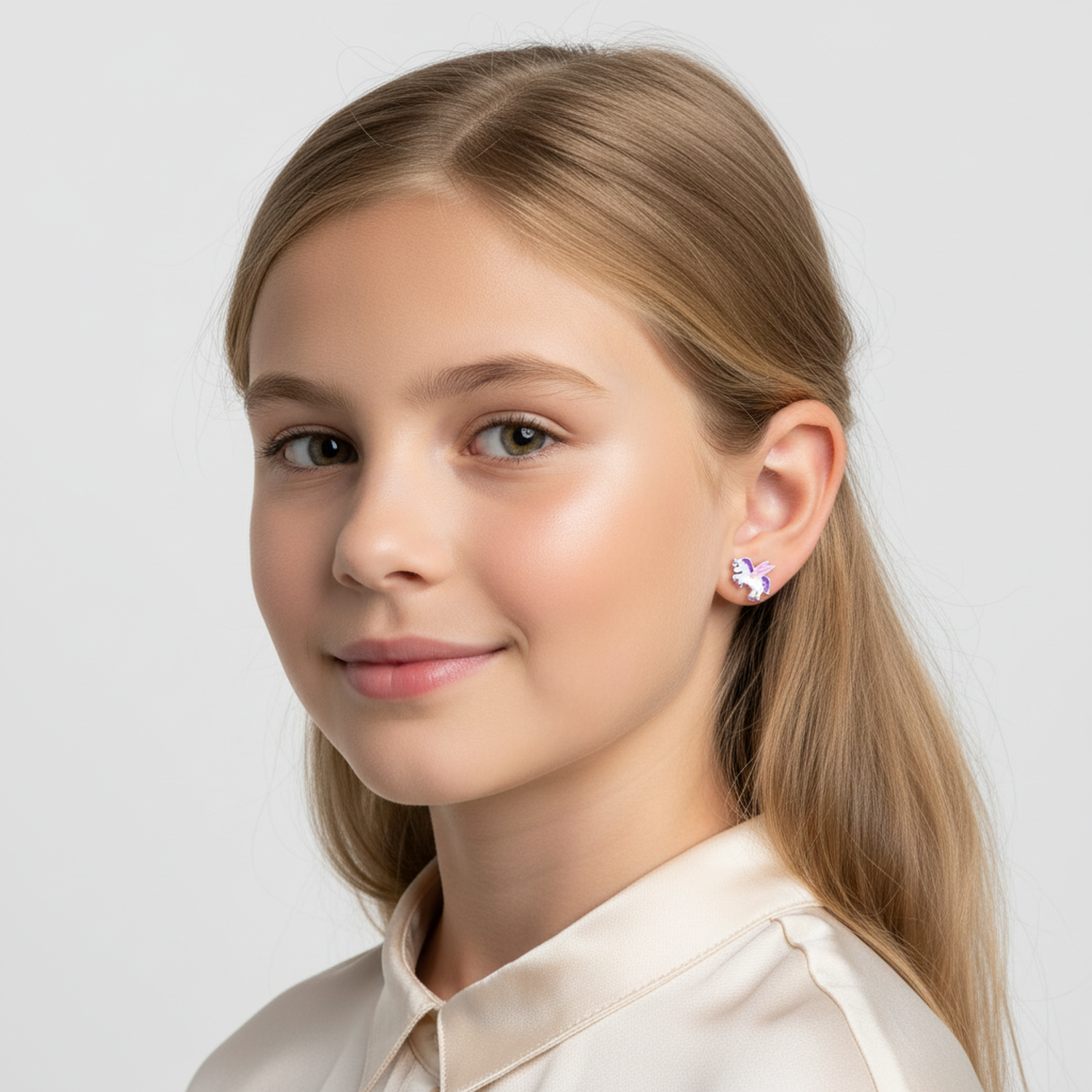 Sterling silver kids earrings unicorn design worn by girl with long blonde hair and cream blouse