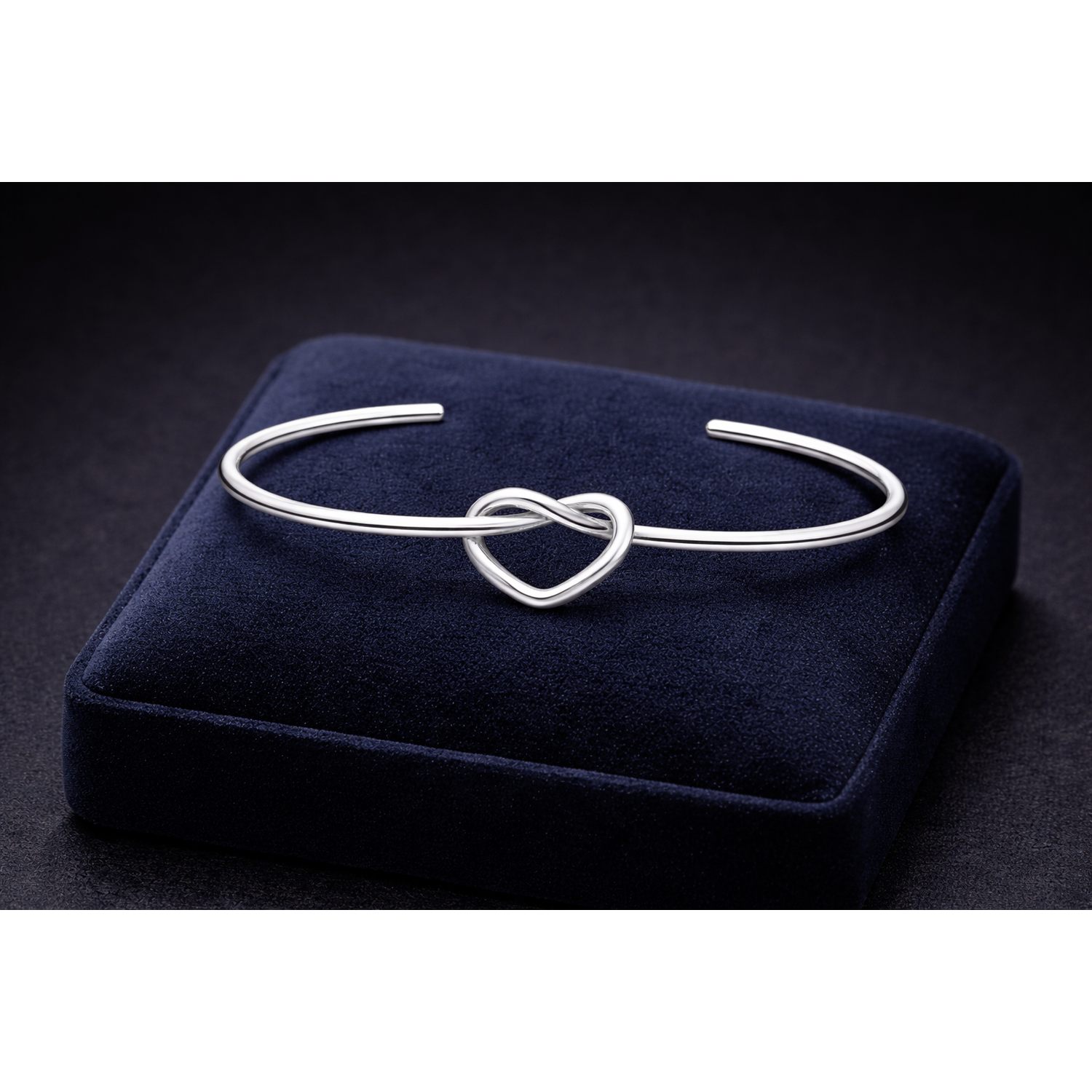Sterling silver love knot bangle by Melchior Jewellery displayed on navy velvet cushion